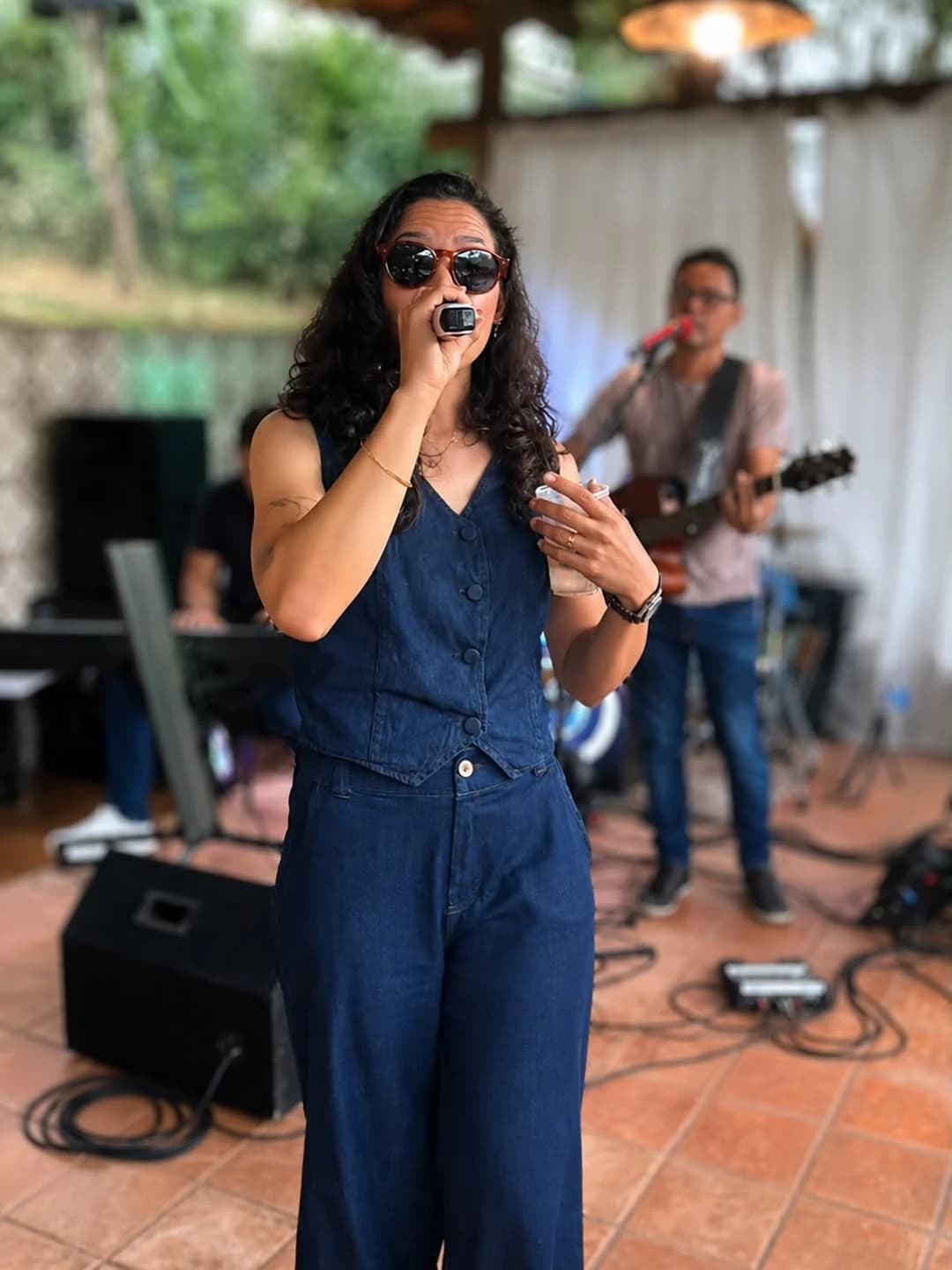 Layra Mota cantando com a banda — guitarra e teclado ao fundo